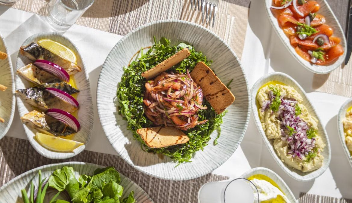 Top-down view of Mediterranean dishes including salads and seafood on an elegant table setting.